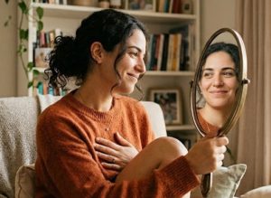 אישה מביטה בעצמה במראה ומחייכת