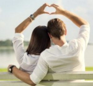 גבר ואישה מצולמים מהגב, מחוברים ויוצרים עם ידים לב מעל ראשם